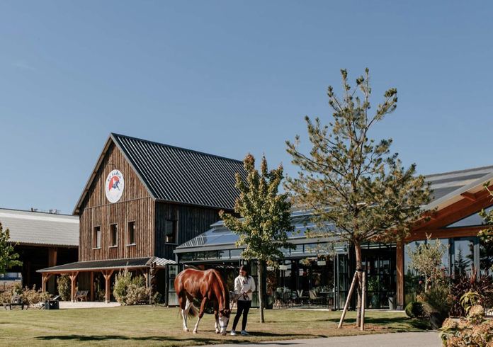 Le bâtiment principal de Bo Ranch et un cheval en main sur la pelouse